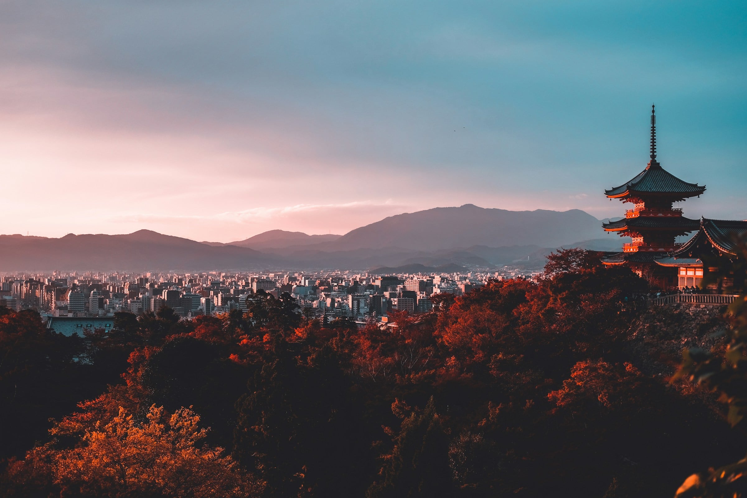 A pagoda above Kyoto at sunset, framed by autumn momiji